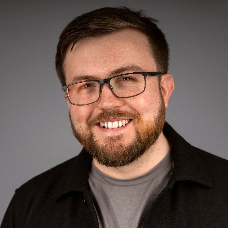 A professional headshot of Toby, smiling at the camera